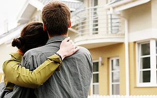 Woman and Man hugging in front of concrete house HD wallpaper