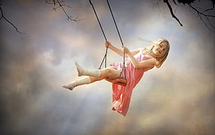 girl wearing pink dress swinging on tree during daytime