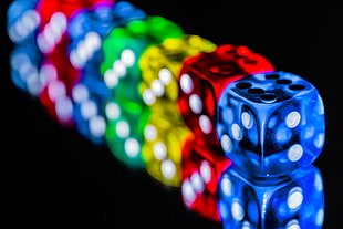 blue, green, red, and yellow dice on black surface