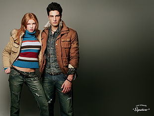 man in brown jacket and blue jeans beside the woman in brown jacket with gray jeans outfit HD wallpaper