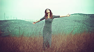 woman in black and white stripe long sleeve dress standing on brown grasses