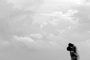 grayscale photo of man and woman under white clouds