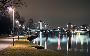 lighted high and mid-rise buildings near body of water and bridge