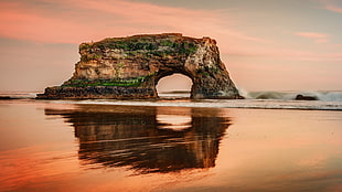 landscape photography of rock archway near body of water