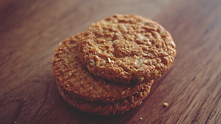 selective focus photography of three stacked cookies on top of brown wooden surface