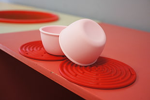 two white plastic bowls on red table