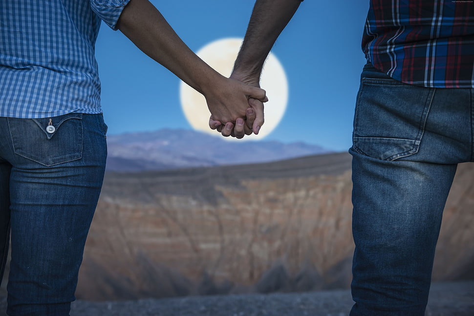 couple holding hands in front of moon HD wallpaper