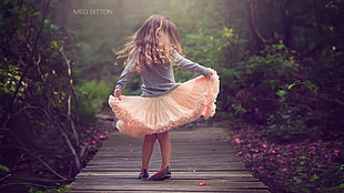 girl lifting her orange dress on wooden dock