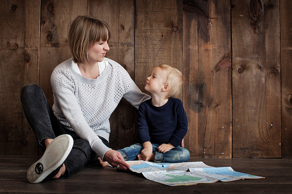 woman smiling with boy while sitting together HD wallpaper