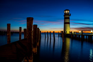 lighthouse near body of water during night time