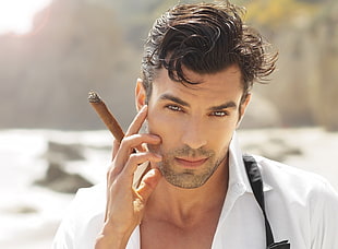 man in white collared shirt holding tobacco during daytime