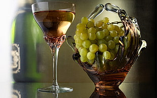 green grapes in clear and red glass fruit basket and clear wine glass
