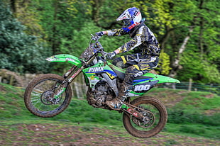 shallow focus photography of person on green #100 motocross dirt bike