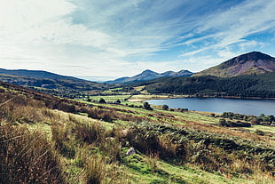 landscape photo of lake between mountain and clear field grass during daytime, snowdonia