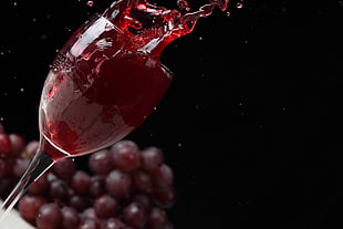 clear wine glass with red wine and red grapes background