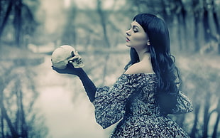 woman wearing black and white off-shoulder dress holding white skull