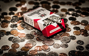 Marlboro cigarette box near round silver-colored coins