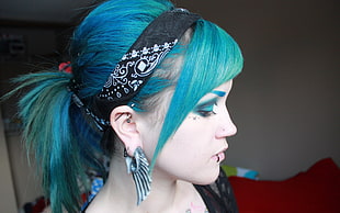 woman with green dyed hair and wearing silver-colored wing earring