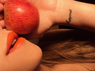 woman with wrist tattoo  holding apple