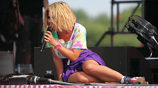 woman sitting on stage while singing