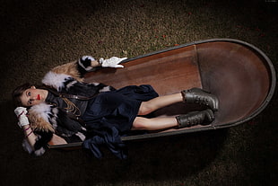 woman wearing black dress and fur cardigan laying on brown oval tub