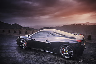landscape photography of black Ferrari sports car on roadway under cloudy sky during daytime