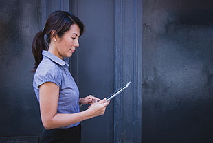 woman wearing blue collared top while holding tablet computer
