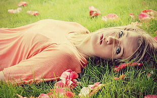 woman lying on grass with flowers at daytime