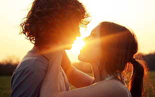 woman holding man neck during sunset