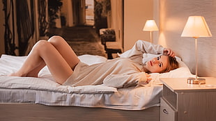 woman wearing long-sleeved dress lying on white bed comforter set