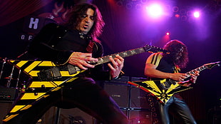 two men with long hair playing electronic guitars