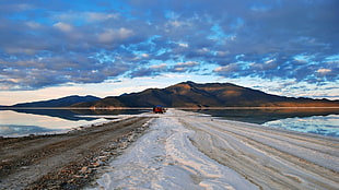 straight sand road beside body of water, landscape