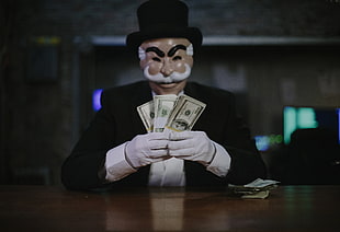 man in black suit holding bundle of money