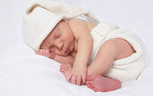 baby wearing white knitted underwear on bed