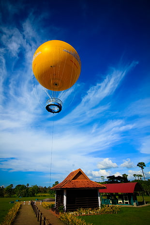 yellow hot air balloon over brown and black house HD wallpaper