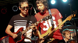 two men's playing electric guitar during concert