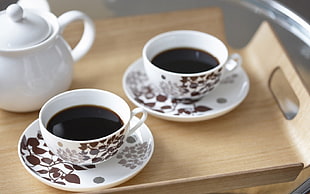 two cup of coffees on saucers on wooden tabletop