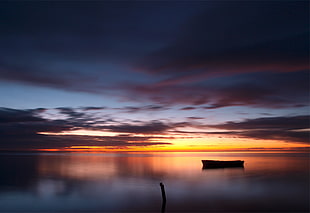 panoramic photography of silhouette of boat on body of water during golden hour