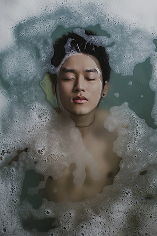 man with black necklace in body of water with bubbles