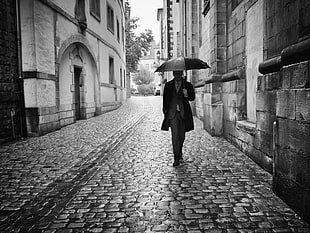 grayscale photography of man walking on hallway and holding umbrella at daytime, luxembourg