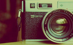 selective color photography of camera on brown wooden surface