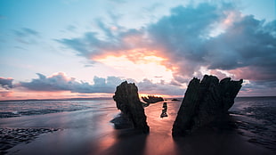 silhouette of two formation of rocks on seashore