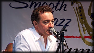 man in white dress shirt in front of microphone