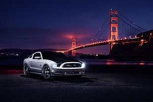 photography of silver Ford Mustang on asphalt road near bridge during nighttime