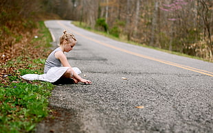girl sitting near on road during daytime