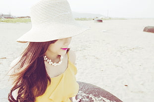 woman in yellow dress wearing sunhat on beach during day time