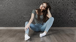 woman wearing gray and black striped shirt and blue denim fitted jeans with socks sits on floor inside the room HD wallpaper