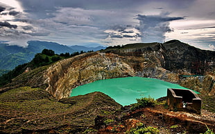 photo of brown mountain with green lake