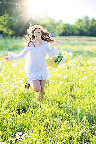 woman running through green grass field holding a flower basket during daytime HD wallpaper