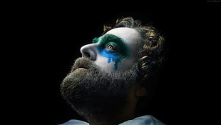 green and blue painted under eye of man